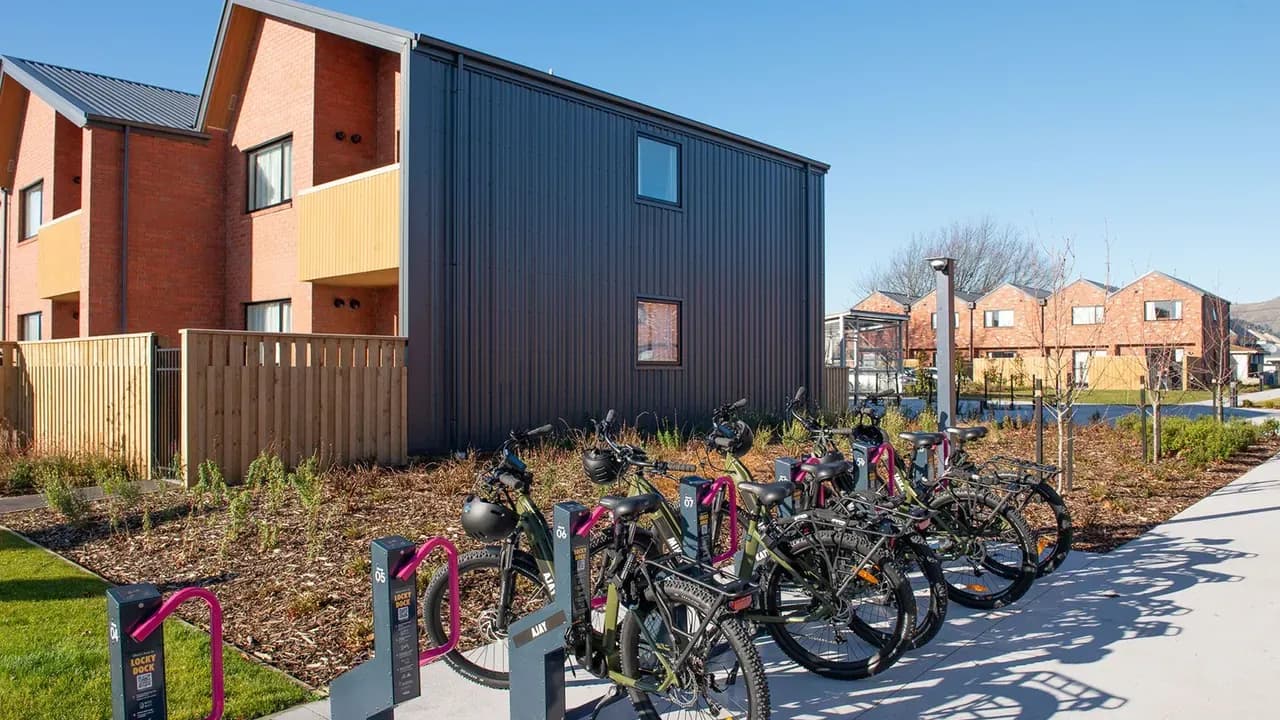 E-bikes locked in pink-armed Locky Dock stations by a row of new homes in New Zealand