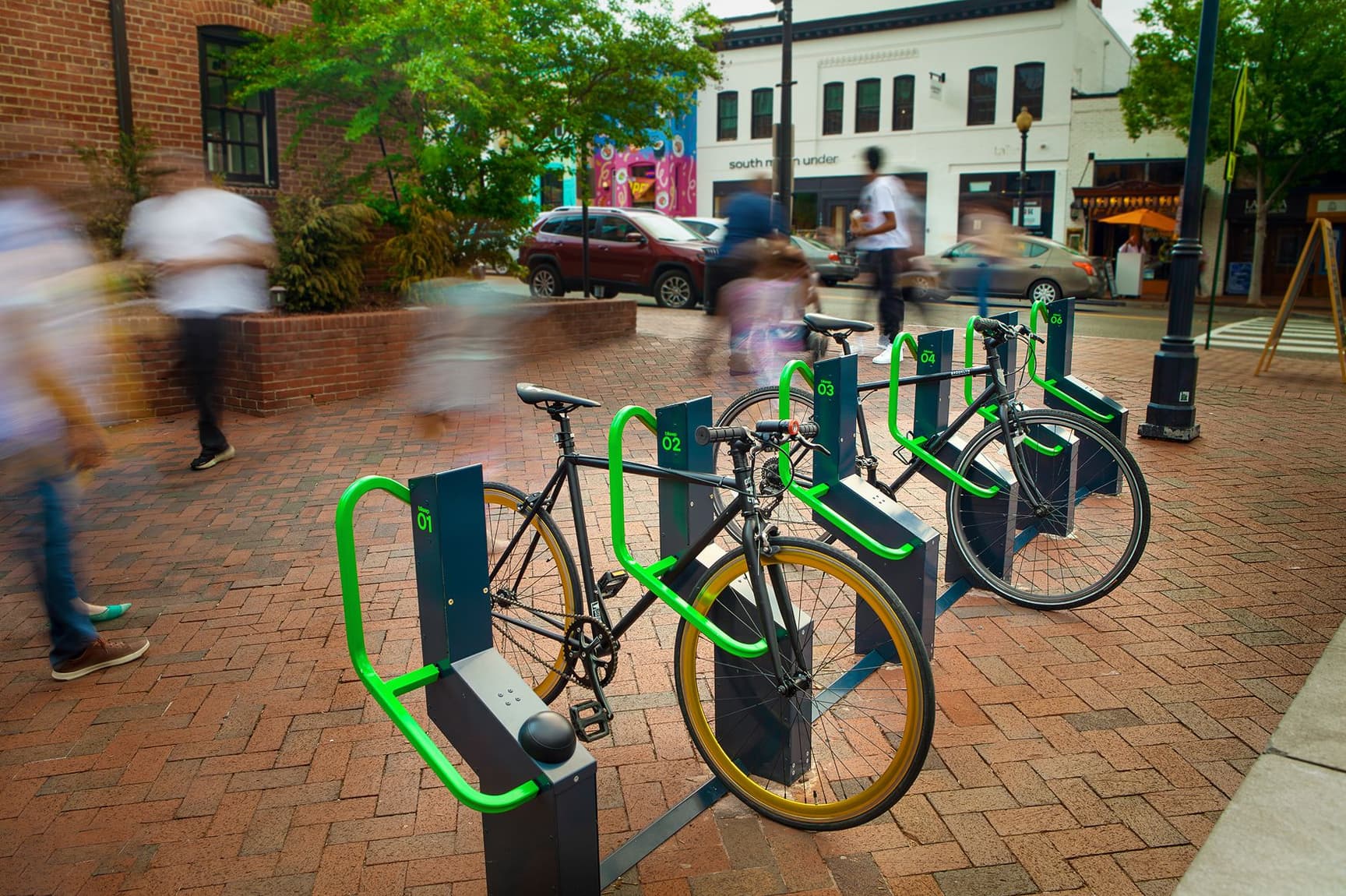 Bikeep smart bike parking station on a busy downtown street with motion-blurred pedestrians, USA