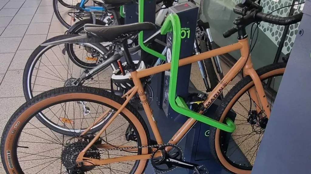 An orange bike locked in a Bikeep e-bike charging dock, with a row of docked bikes behind it on Union Road at UNSW Sydney