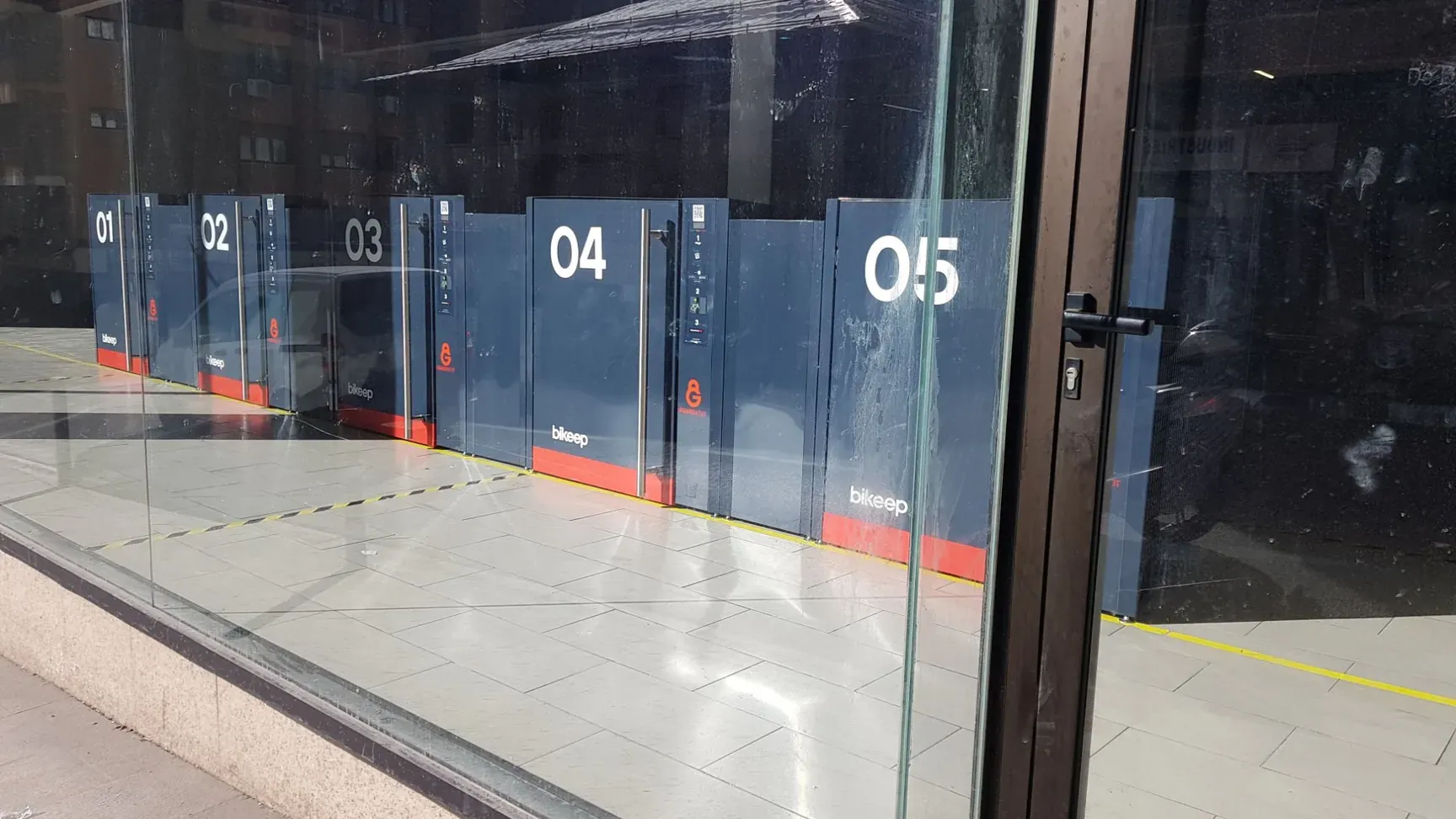 Bikeep smart lockers branded GuardaTOT, numbered 01 to 05, behind a glass storefront in Andorra