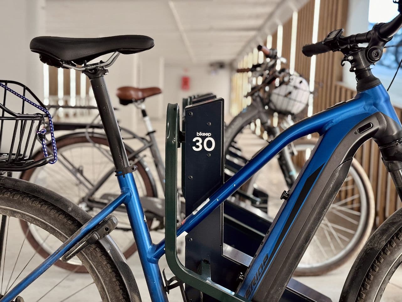 A blue e-bike locked in a Bikeep smart bike parking dock