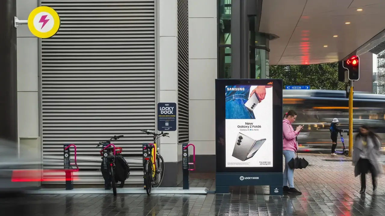 Bikes at a Locky Dock station beside an oOh!media digital advertising screen on Victoria Street, Auckland